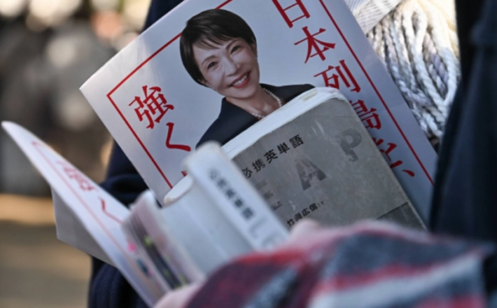A supporter holds a flyer for Prime Minister Sanae Takaichi, who is also president of the Liberal Democratic Party, alongside an English vocabulary book at an LDP election rally in the city of Saitama on Tuesday. | BLOOMBERG