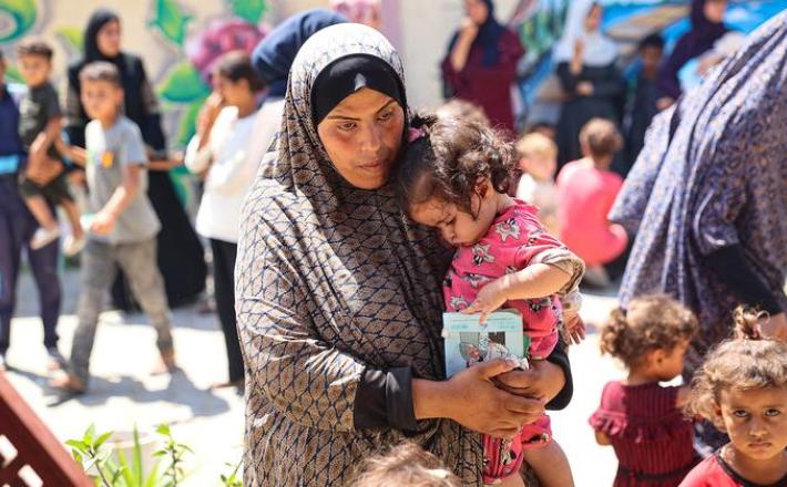 © UNICEF/Eyad El Baba سيدة فلسطينية تحتضن ابنتها أثناء انتظارهما لإجراء فحص التغذية في عيادة تدعمها اليونيسف في قطاع غزة.