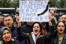 رفعت متظاهرة لافتة كُتب عليها "كل شعرة في رؤوسنا ثمينة كالعالم أجمع"، مع ضفيرة شعر مُعلقة بها، وهي تُردد شعارات خلال مظاهرة تضامنية مع الأكراد في شمال سوريا، في إسطنبول، بتاريخ 24 يناير/كانون الثاني 2026. AFP - YASIN AKGUL