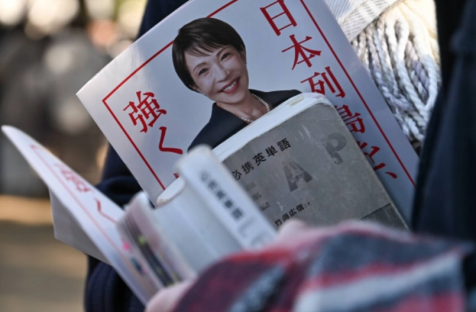 A supporter holds a flyer for Prime Minister Sanae Takaichi, who is also president of the Liberal Democratic Party, alongside an English vocabulary book at an LDP election rally in the city of Saitama on Tuesday. | BLOOMBERG