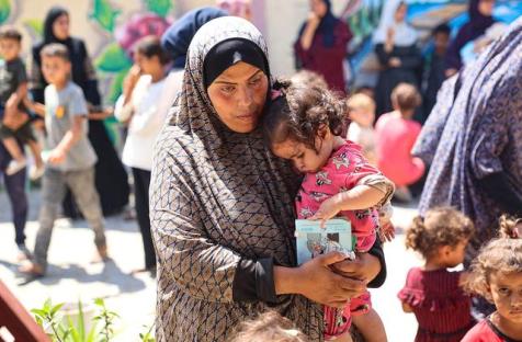 © UNICEF/Eyad El Baba سيدة فلسطينية تحتضن ابنتها أثناء انتظارهما لإجراء فحص التغذية في عيادة تدعمها اليونيسف في قطاع غزة.