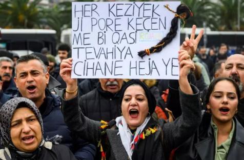 رفعت متظاهرة لافتة كُتب عليها "كل شعرة في رؤوسنا ثمينة كالعالم أجمع"، مع ضفيرة شعر مُعلقة بها، وهي تُردد شعارات خلال مظاهرة تضامنية مع الأكراد في شمال سوريا، في إسطنبول، بتاريخ 24 يناير/كانون الثاني 2026. AFP - YASIN AKGUL